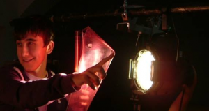 Young person inserting lighting gel to theatre light