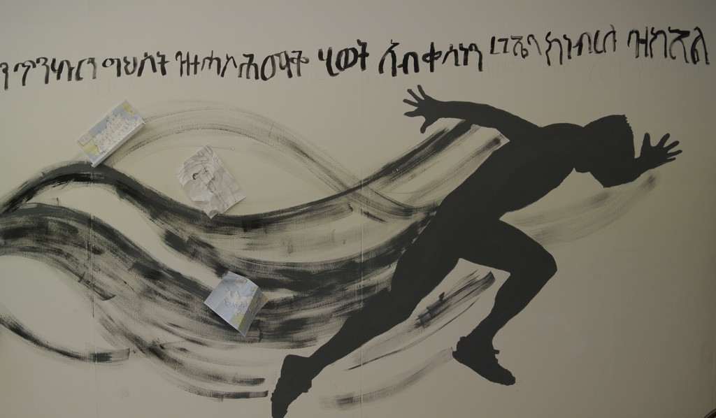 Silhouette of a man running, with writing in Tigrean script
