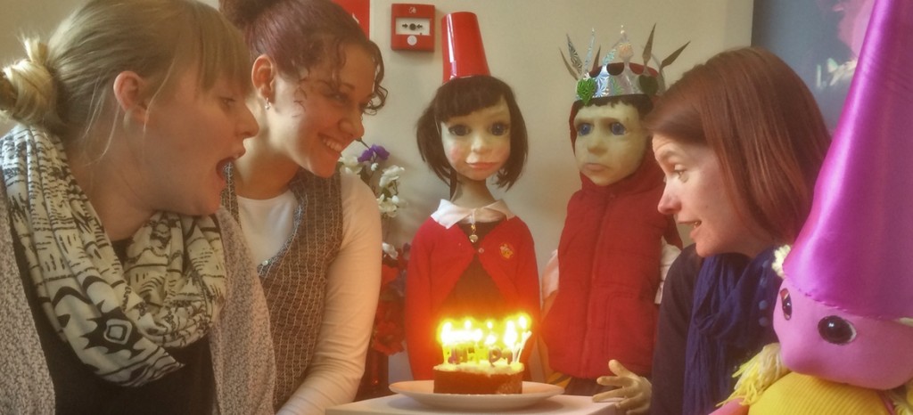 Staff and Ken and Bee puppets celebrate our tenth birthday with cake and candles