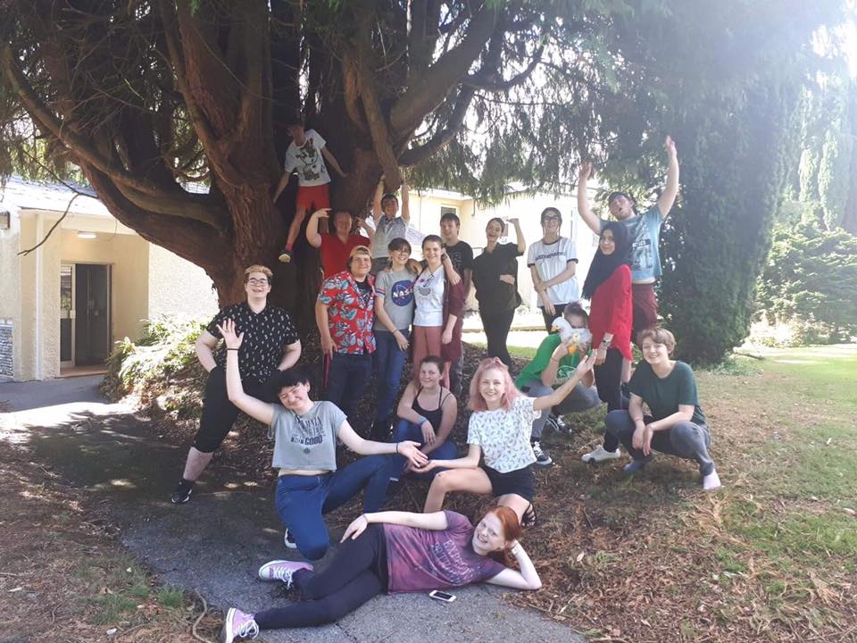 a group of young people outside under a tree celebrating the end of training