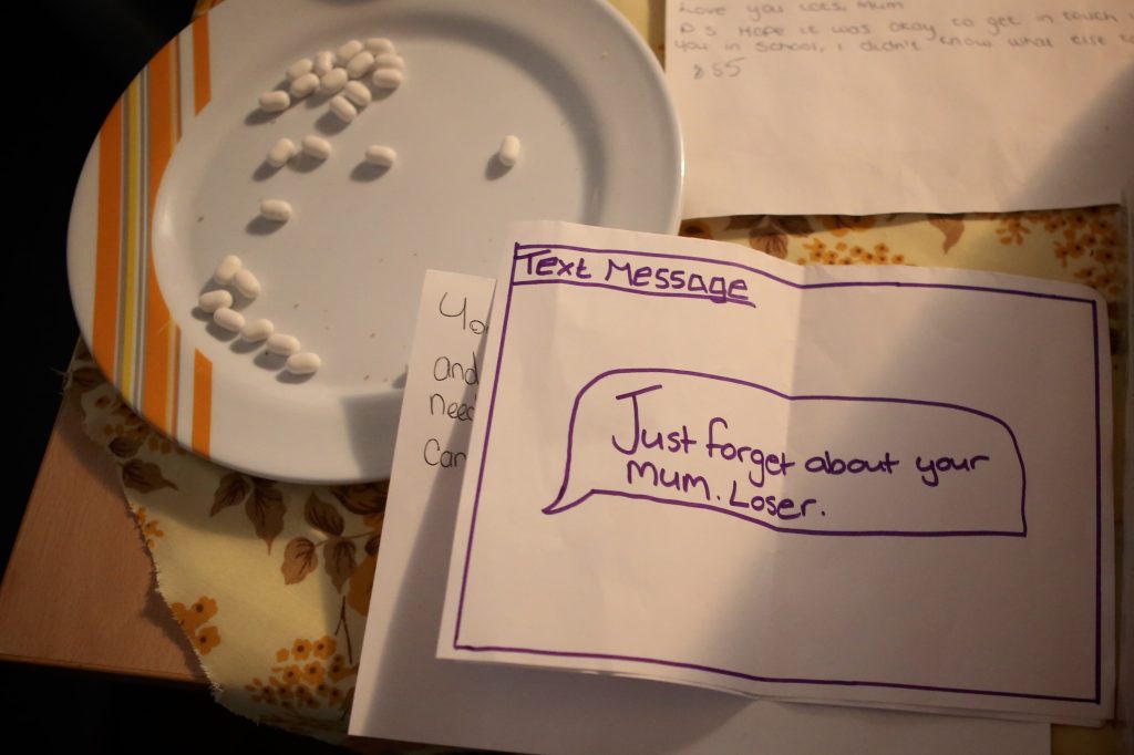 A plate of pills and a note reading Text Message: Just forget about your mum loser'